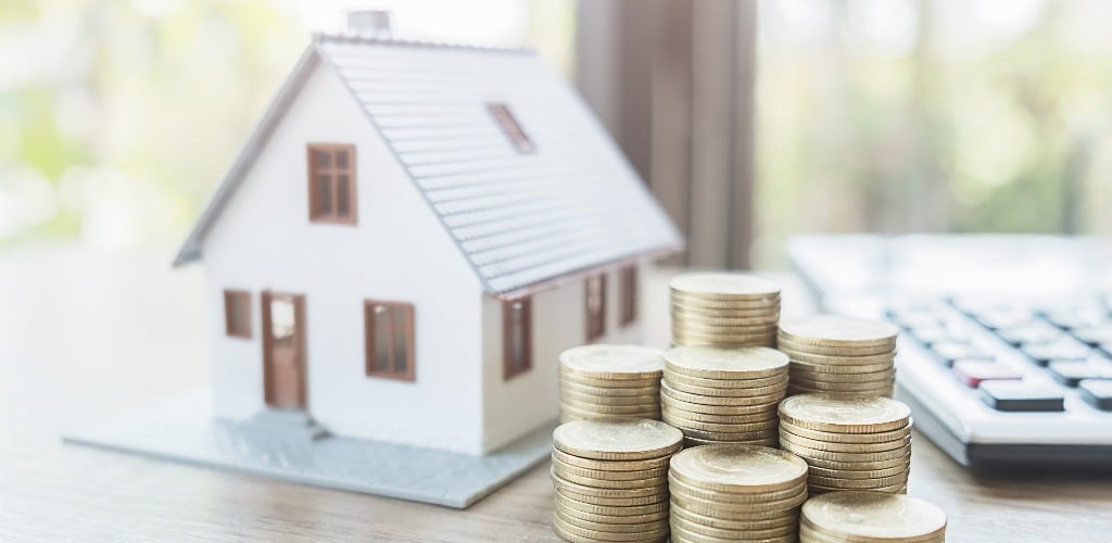 Miniaturhaus und Geld: Symbol für Zinshaus als sichere Anlage